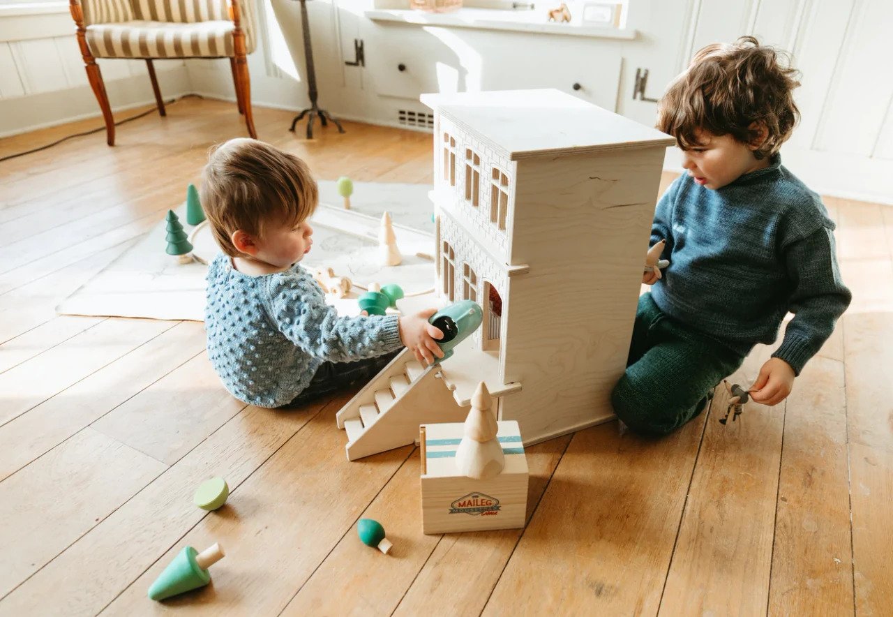 Children playing together with a wooden dollhouse
